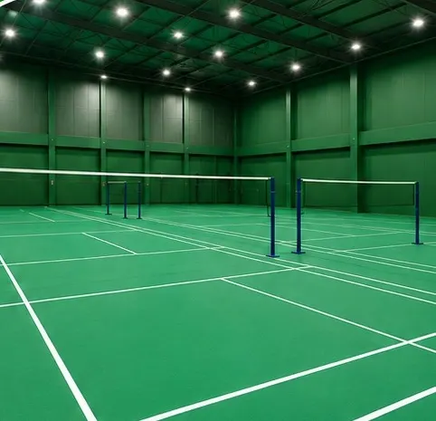 Indoor badminton hall with green court surface, white lines and nets